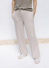 Model wearing tan wide leg pants with pockets, rayon material and a tie at the waist. 