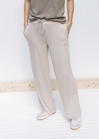 Model wearing tan wide leg pants with pockets, rayon material and a tie at the waist. 