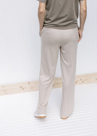 Back view of Model wearing tan wide leg pants with pockets, rayon material and a tie at the waist. 