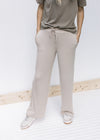 Model wearing a sage top and tan wide leg pants with pockets, rayon material and a tie at the waist.