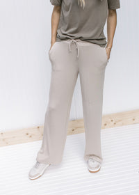 Model wearing a sage top and tan wide leg pants with pockets, rayon material and a tie at the waist.