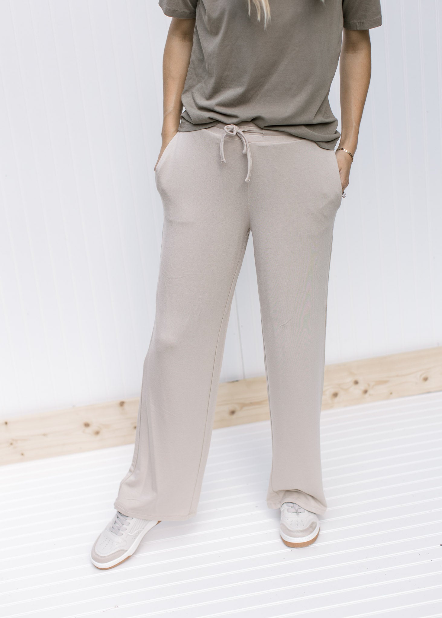Model wearing a sage top and tan wide leg pants with pockets, rayon material and a tie at the waist.