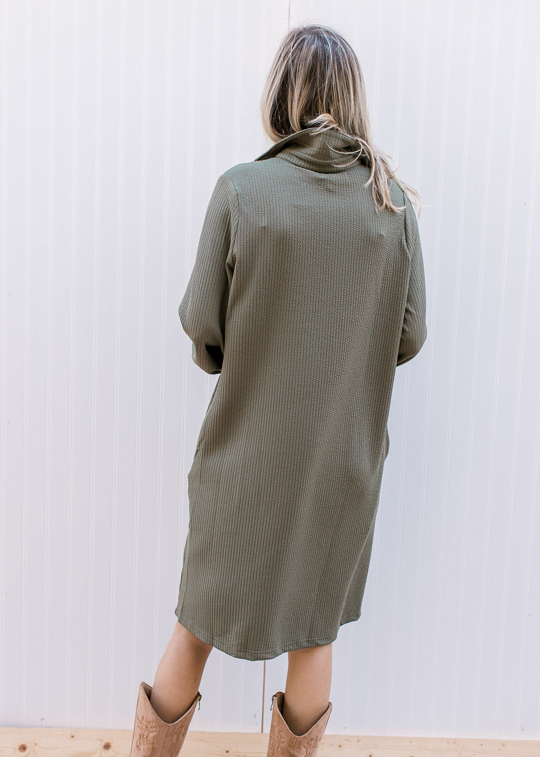 Back view of Model wearing an olive ribbed midi with a collar, long sleeves and a patch pocket. 