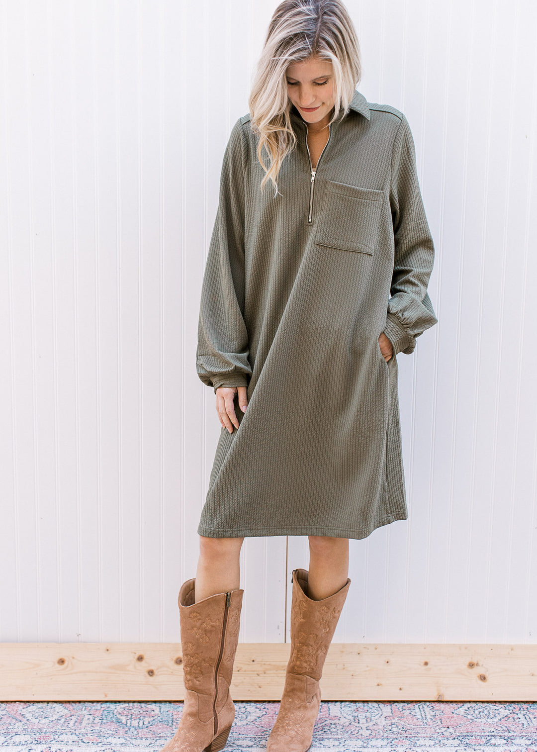 Model wearing boots and an olive midi with a quarter zip neck, long sleeves and a patch pocket. 