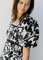 Close up of short puff sleeve on a cream top with black floral and a square neck. 