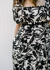 Close up of square neck and scallop detail on a short sleeve cream dress with black floral.