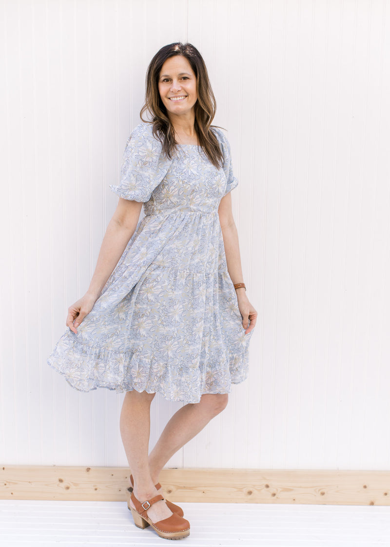 Model wearing a baby blue above the knee dress with sketched floral pattern and square neckline