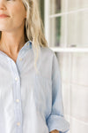 Close up of patch pockets and buttons on a light blue top with long sleeves.