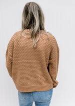 Back view of Model wearing a copper colored sweater with a basket weave stitch and long sleeves. 