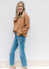 Model wearing jeans, mules and a copper colored sweater with a basket weave stitch and long sleeves.