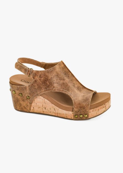 Outside view of a cognac wedge with 3” heel to 1” platform, a slip-on design and adjustable strap. 
