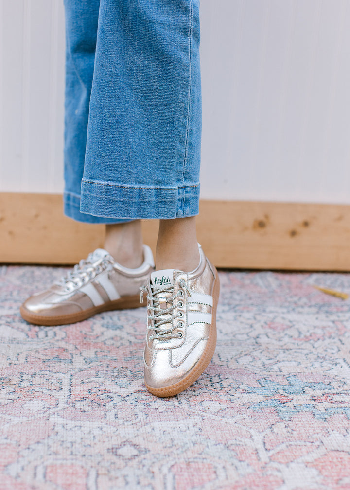 Model wearing a gold retro, low-top sneakers with sparkle laces gum rubber sole.