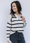 Model wearing a white long sleeve sweater with black stripes, a split hem and a collard v-neck. 