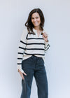Model wearing a white long sleeve sweater with black stripes, a split hem and an acrylic material. 