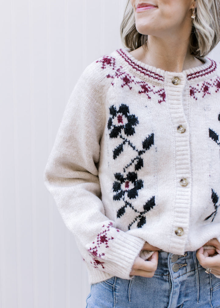 Model wearing a cream button up cardigan with navy floral, burgundy detailing and long sleeves. 