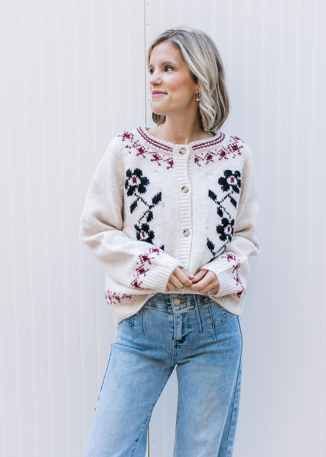 Model wearing a cream cardigan with navy floral, burgundy detailing and long sleeves. 