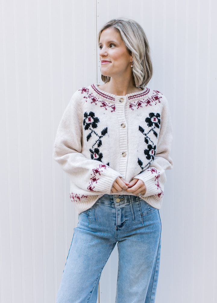 Model wearing a cream cardigan with navy floral, burgundy detailing and long sleeves. 