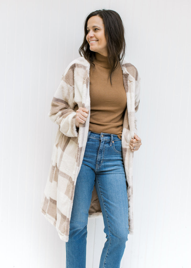 Model wearing a camel top with a cream, tan and brown plaid knee length coat with an open front. 