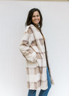 Model wearing a cream, tan and brown plaid coat with an open front, pockets and long sleeves. 