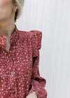 Close up of corduroy fabric on a rust button up dress with long sleeves and cream flowers.