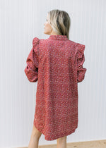 Back view of Model wearing a rust dress with cream ditsy floral and long sleeves. 