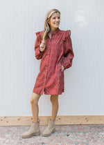 Model wearing booties and a rust dress with cream floral, button front and ruffle at the shoulder. 