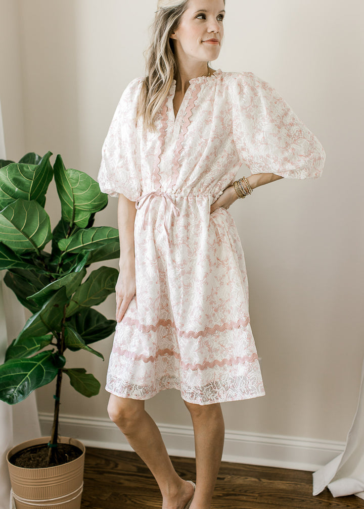 Model wearing a cream above the knee dress with lace overlay with blush floral and 3/4 sleeves.