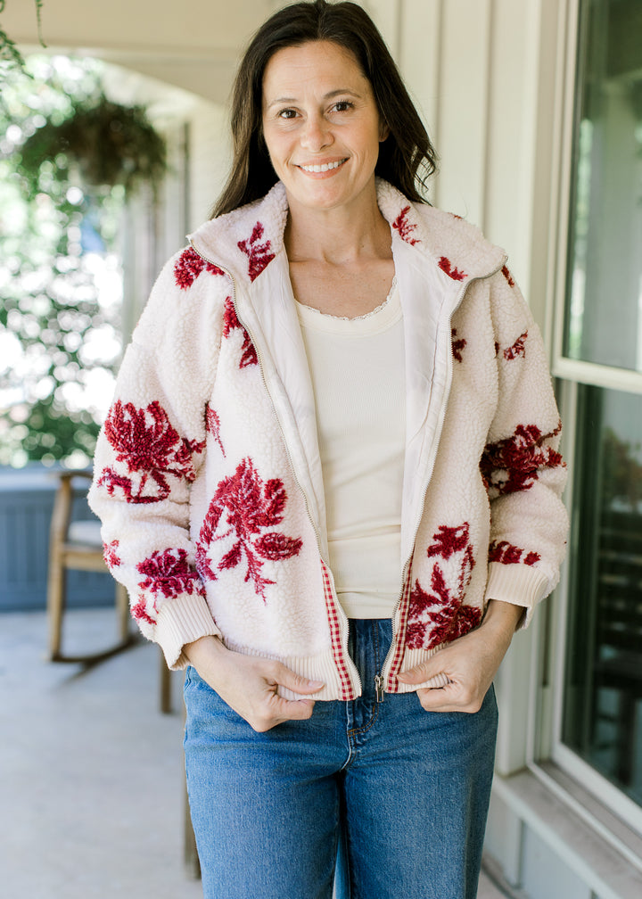 Model wearing a cozy plush jacket with cream with burgundy floral, mock neck and long sleeves. 