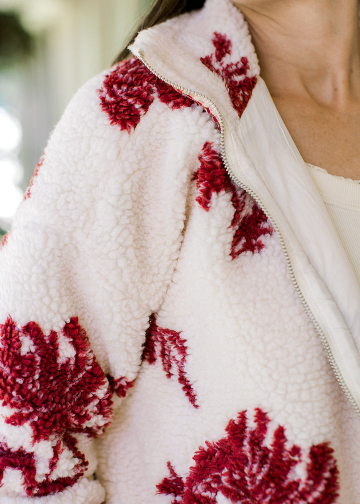 Close up of cozy plush and zipper closure on a cream jacket with burgundy floral and mock neck.