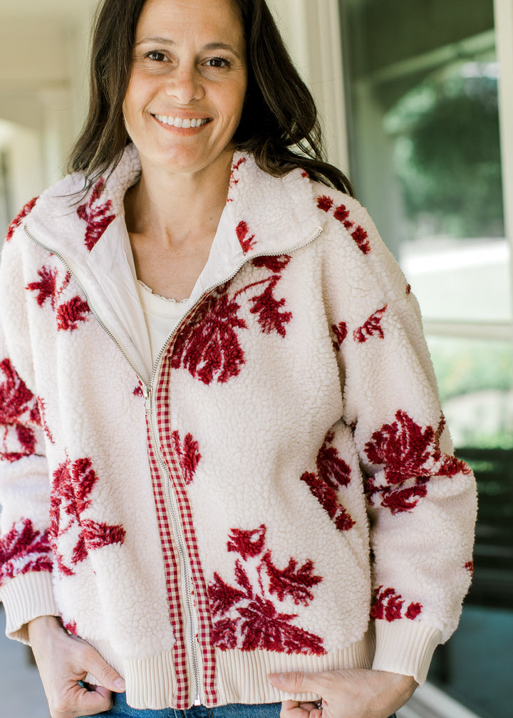 Model wearing a cozy zippped jacket with cream with burgundy floral, mock neck and long sleeves. 