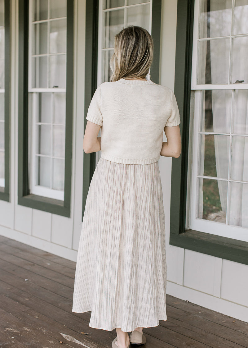 Back view of Model wearing a midi and a cream cardigan with short sleeves and ribbing. 