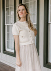 Model wearing a cream sweater over a sleeveless midi dress with a taupe skirt and black stripes.