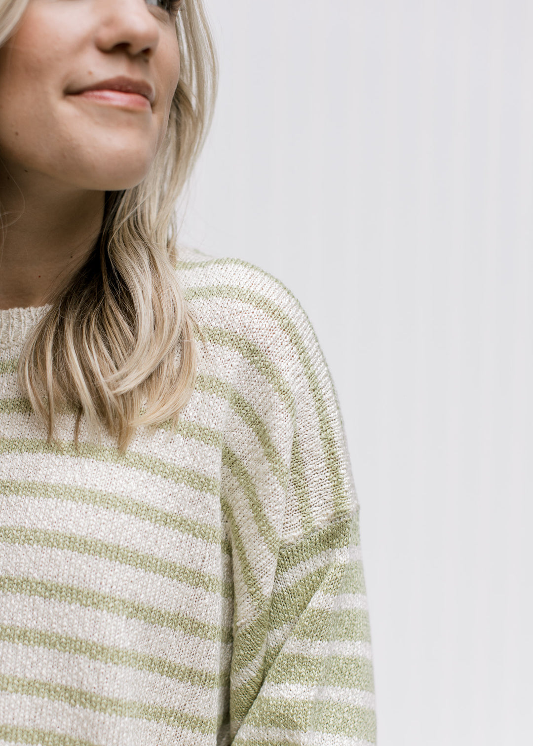 Close up of inverted pattern on the sleeve of a cream and lime sweater with an acrylic material. 