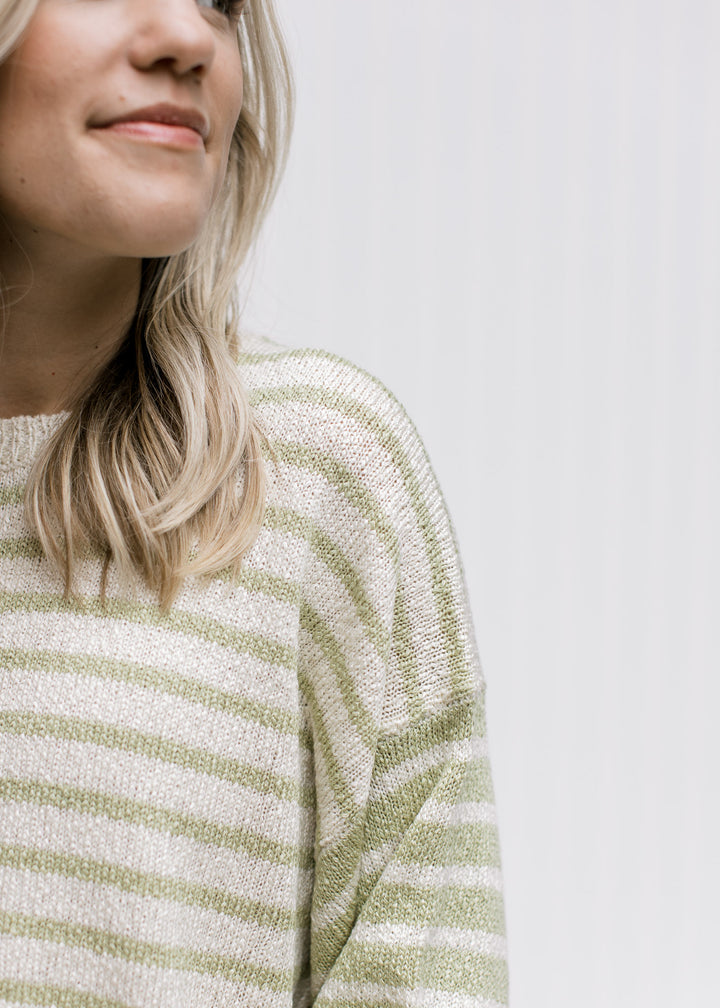 Close up of inverted pattern on the sleeve of a cream and lime sweater with an acrylic material. 