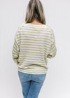 Back view of Model wearing a cream and lime striped sweater with inverted pattern on the sleeves.