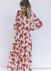 Model wearing a cream maxi with rust floral pattern, long sleeves with elastic cuff and v-neck.
