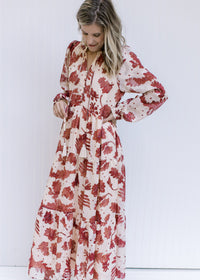 Model wearing a cream maxi with rust floral pattern, long sleeves with elastic cuff and v-neck.