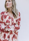 Close up of v-neck with ruffle and tie on a cream dress with a rust floral pattern and long sleeves.