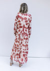 Back view of Model wearing a cream maxi with rust floral pattern, long sleeves and a v-neck.