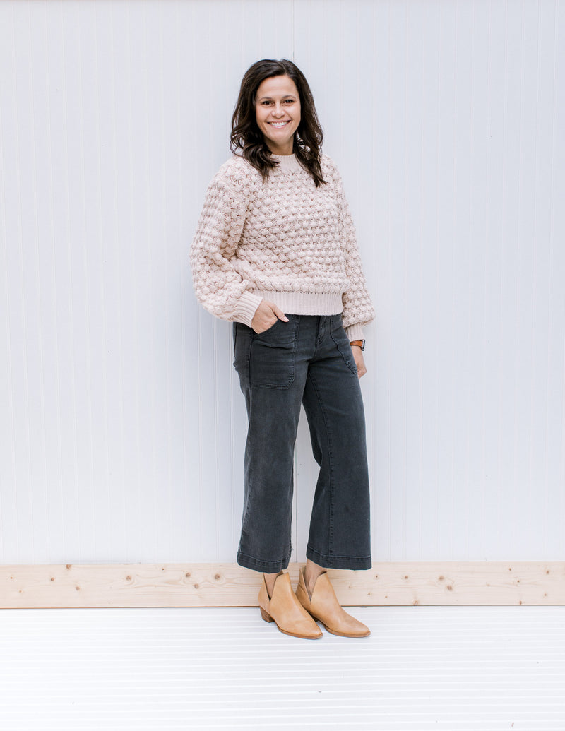 Model wearing jeans, mules and a cream bubble knit sweater with bubble long sleeves.