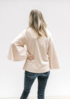 Back view of Model wearing a cream cotton top with a round neck and 3/4 butterfly sleeves. 