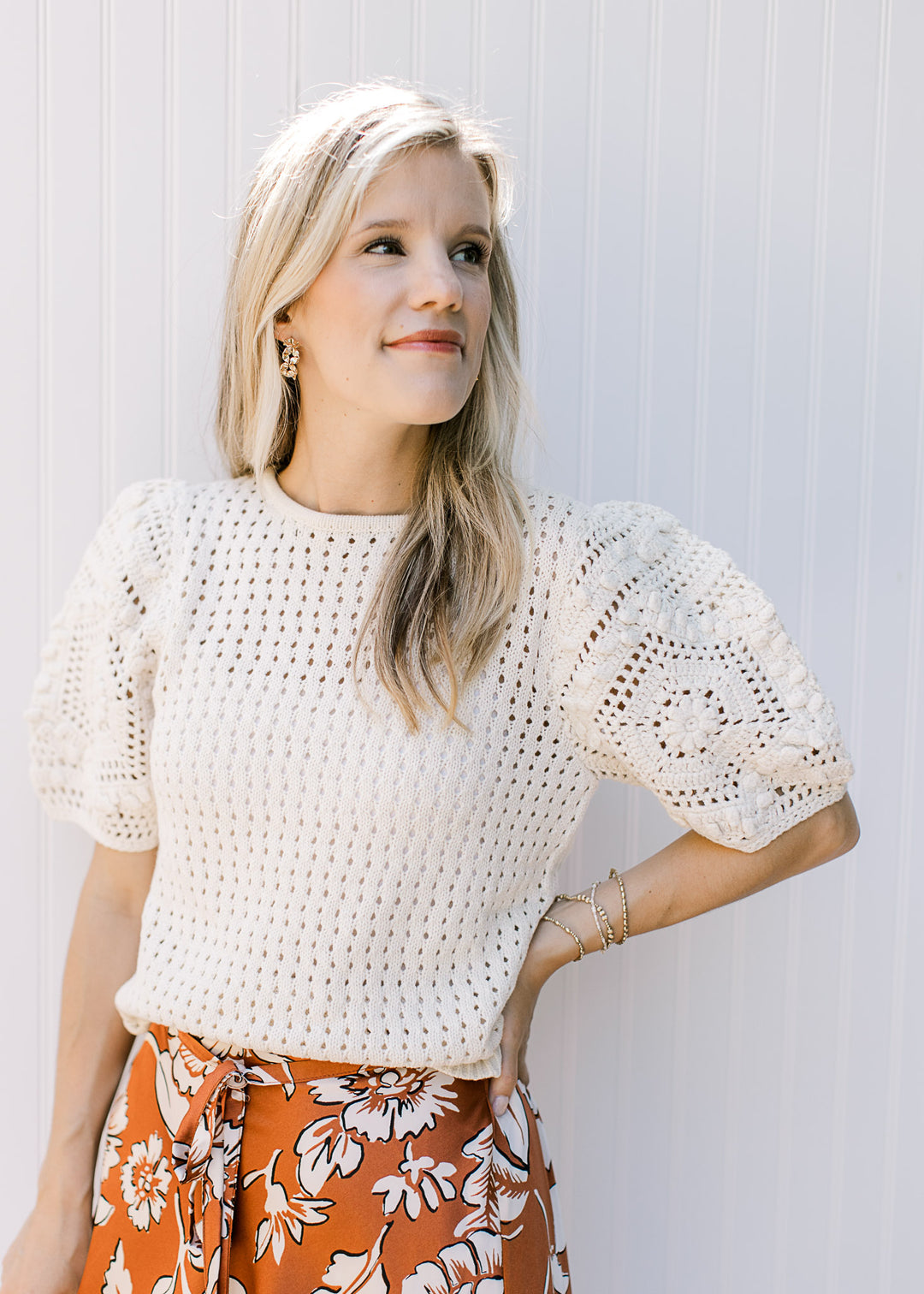 Model wearing a cream short sleeve crochet sweater with a ribbed hem. 