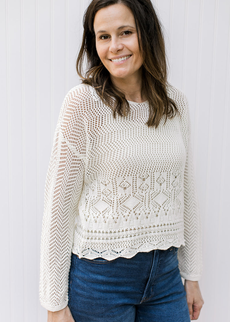 Model wearing a slightly cropped cream crochet sweater with long sleeves.