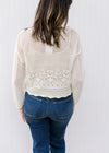 Back view of Model wearing a slightly cropped cream crochet sweater with a scalloped hem.