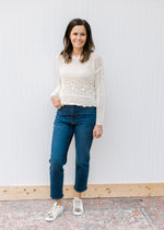 Model wearing jeans with a cream crochet sweater with long sleeves and scalloped hem.