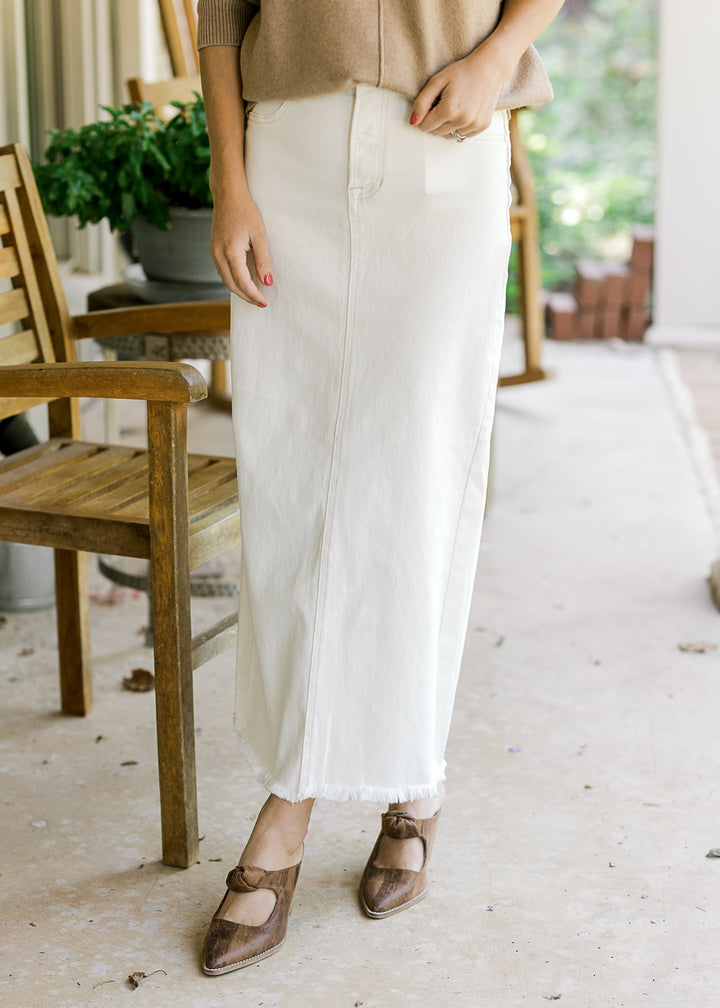 Model wearing a cream denim maxi with faux front pockets, raw hemline and two back pockets.