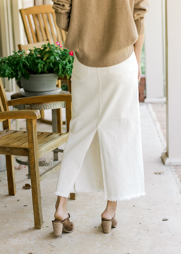 Back view of Model wearing a cream denim maxi with split,raw hemline and two back pockets.