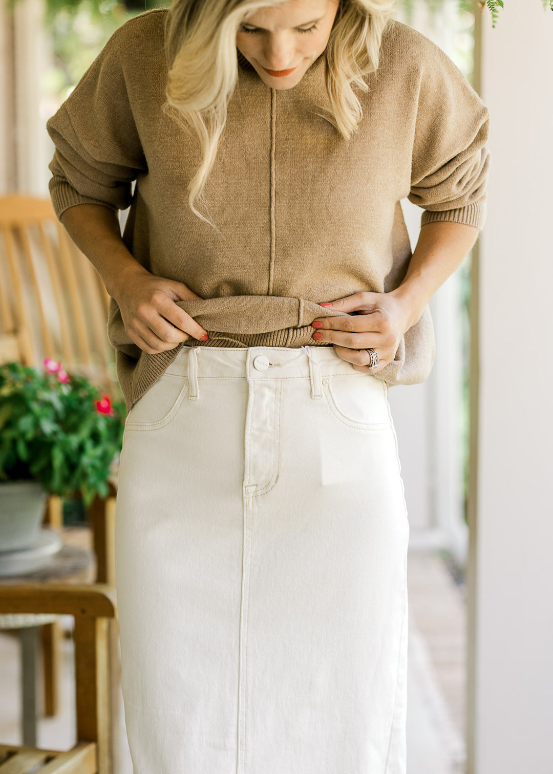 Model wearing a cream denim maxi with traditional button closure, raw hem and two back pockets.