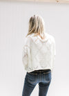 Back view of Model wearing a cream crop fit sweater with diamond open stitch detail and long sleeves