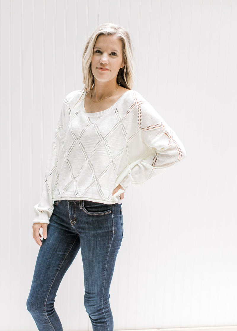 Model wearing jeans with a cream crop fit sweater with diamond open stitch detail and long sleeves.